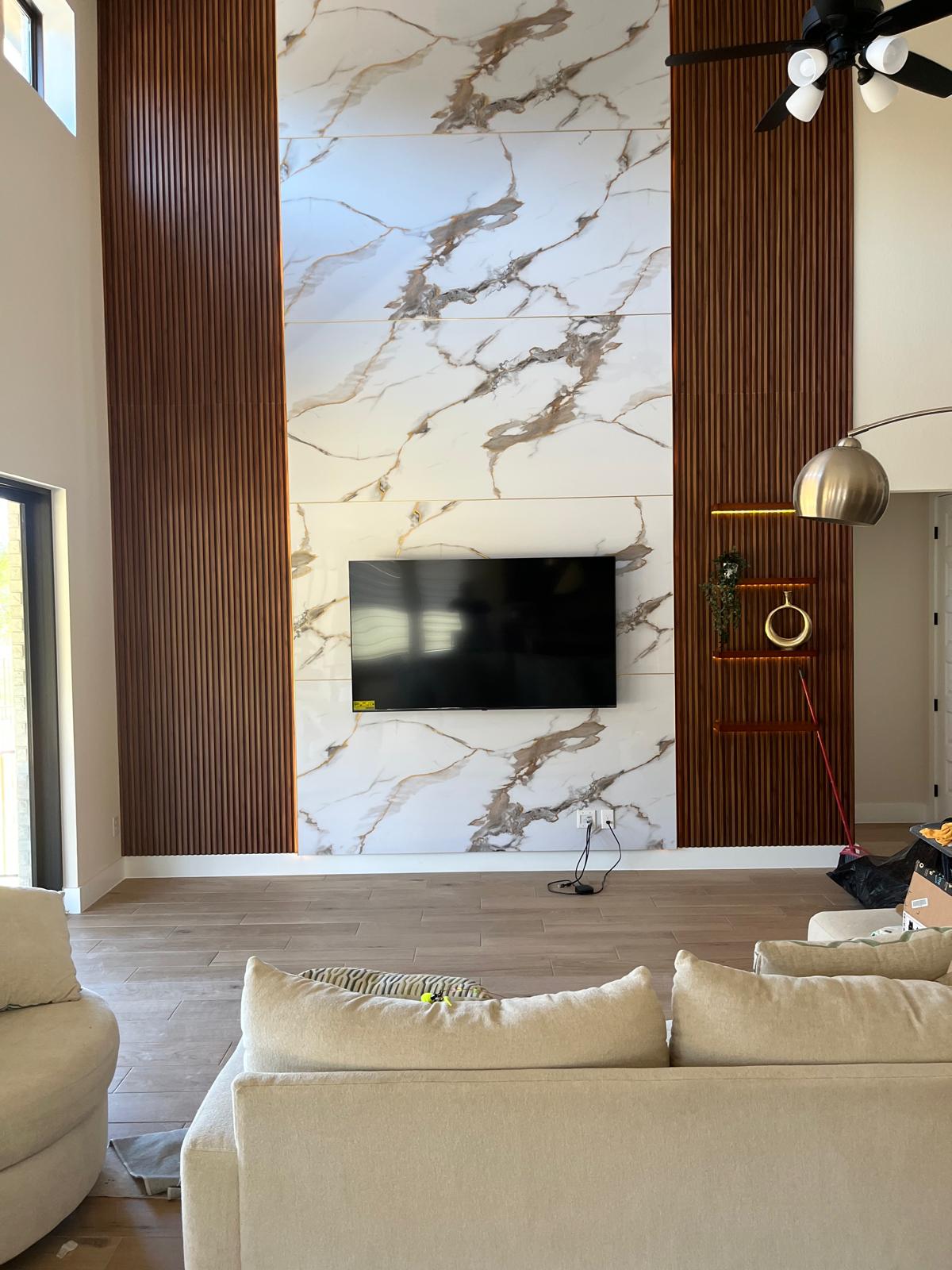 Finished TV wall with marble-look panels and wood-tone fluted accents